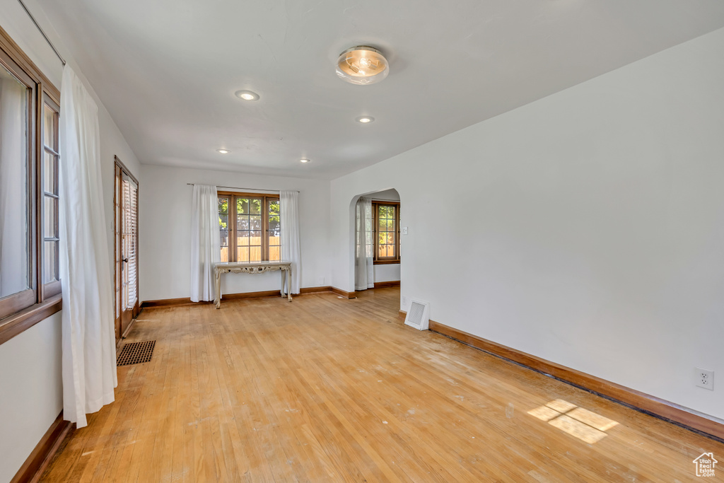 Unfurnished room featuring arched walkways, light wood-style flooring, and recessed lighting