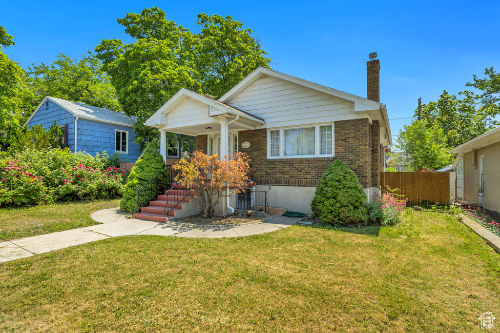 Bungalow-style home featuring brick siding, a chimney, and a porch
