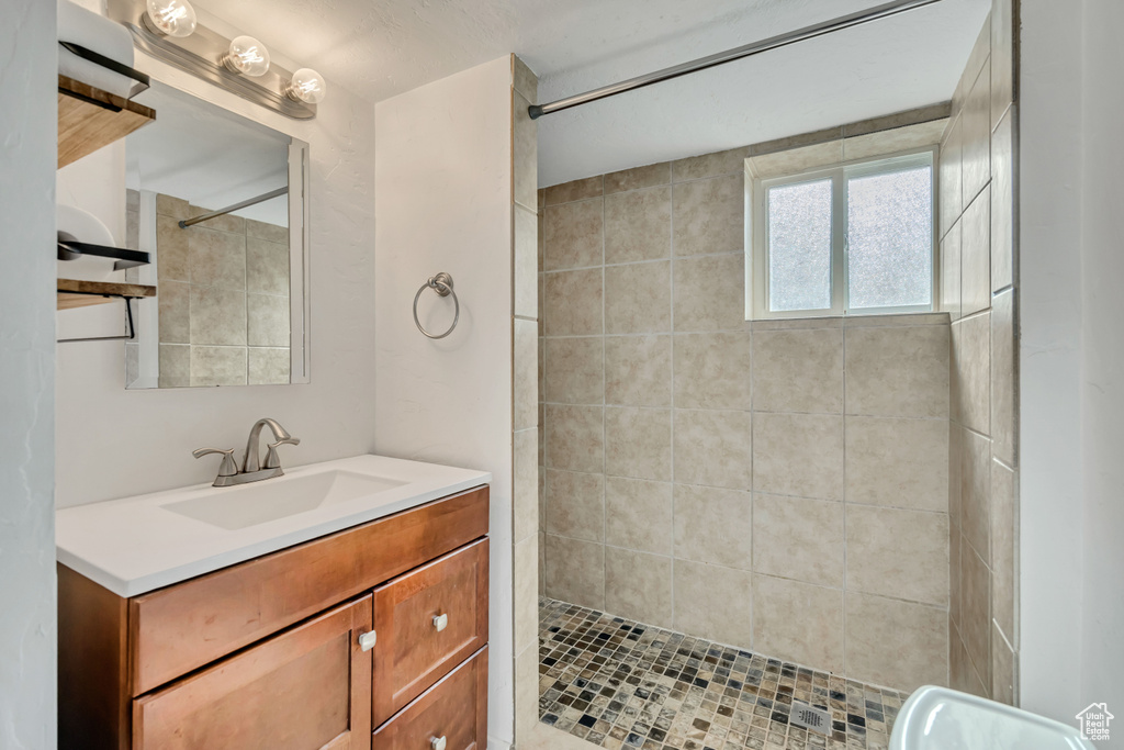 Full bath with tiled shower and vanity