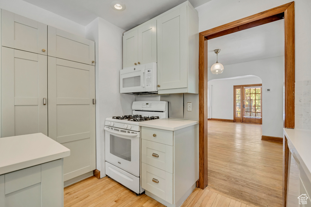 Kitchen featuring white appliances, light wood-style flooring, light countertops, recessed lighting, and arched walkways