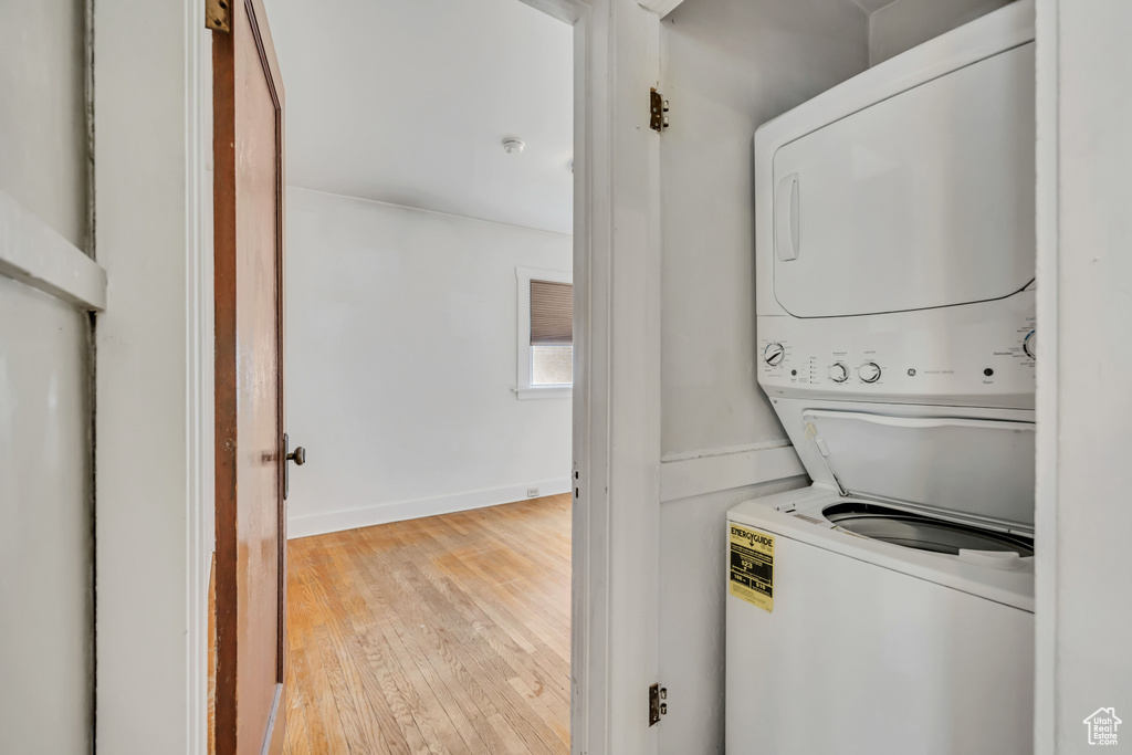 Washroom with stacked washer / dryer and hardwood / wood-style flooring