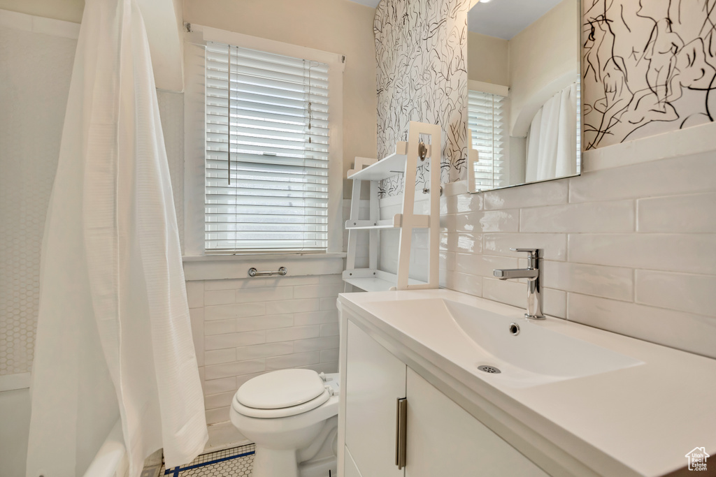 Bathroom with tile walls, vanity, shower / tub combo, and tasteful backsplash
