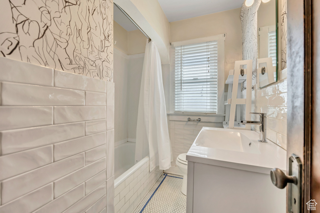 Full bath featuring shower / tub combo, vanity, and tile walls