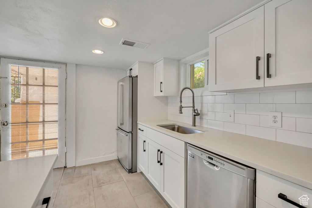 Kitchen featuring appliances with stainless steel finishes, tasteful backsplash, light countertops, white cabinets, and recessed lighting