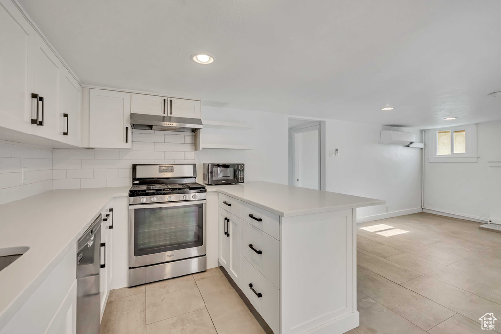 Kitchen featuring stainless steel appliances, under cabinet range hood, a peninsula, light countertops, and recessed lighting