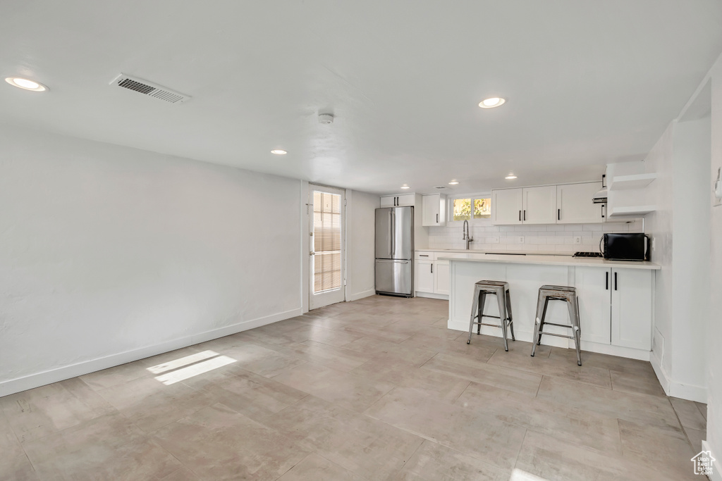 Kitchen featuring freestanding refrigerator, open shelves, white cabinetry, recessed lighting, and light countertops