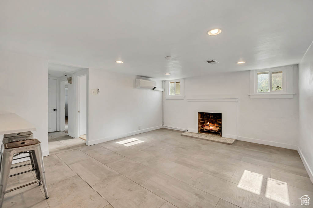 Unfurnished living room with an AC wall unit, a lit fireplace, and recessed lighting