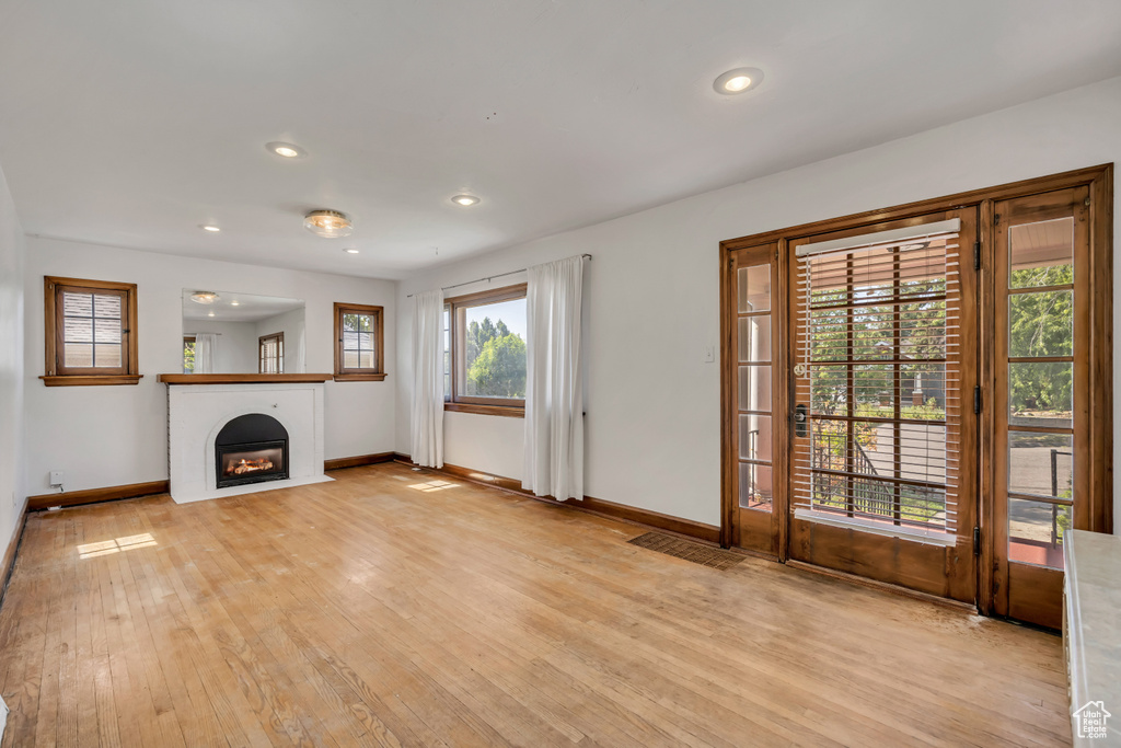 Unfurnished living room with light wood finished floors, a warm lit fireplace, and recessed lighting