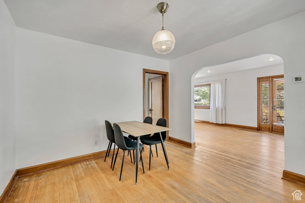 Dining area featuring arched walkways and light wood-style flooring