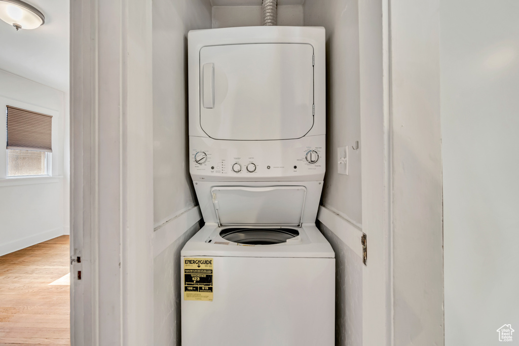 Washroom featuring stacked washer and clothes dryer and wood finished floors