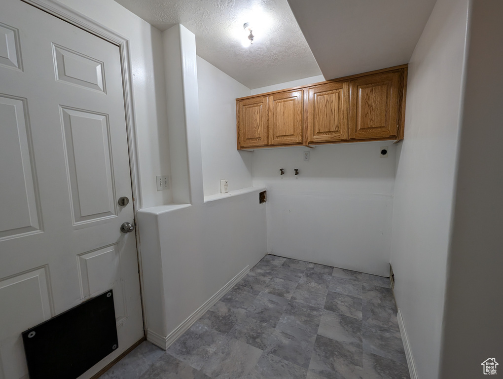 Washroom featuring cabinet space, hookup for an electric dryer, hookup for a washing machine, and stone finish flooring