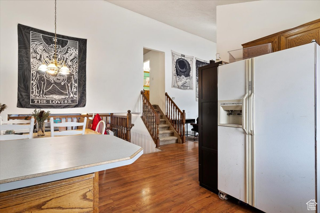 Kitchen with white refrigerator with ice dispenser, a chandelier, and wood finished floors