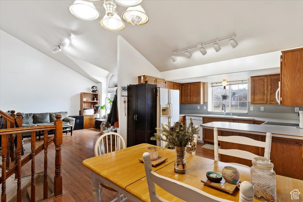 Kitchen with track lighting, light wood-type flooring, white appliances, light countertops, and brown cabinets