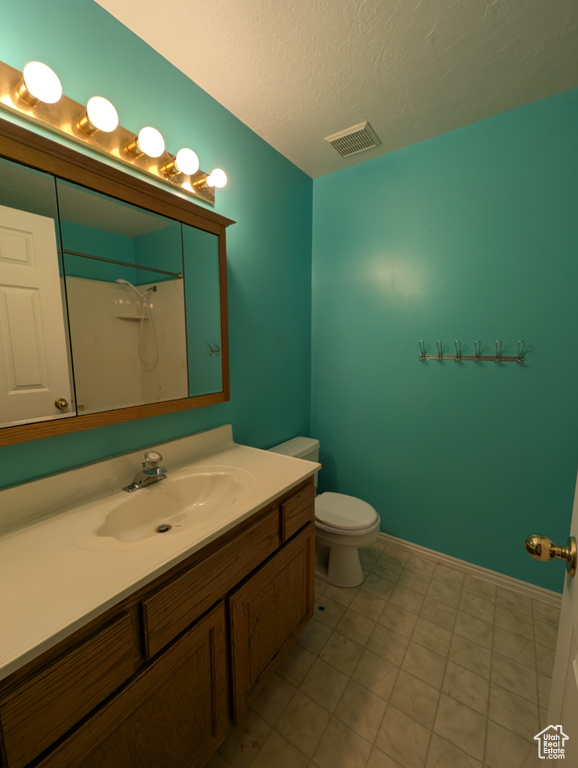 Bathroom featuring vanity, a shower, and a textured ceiling