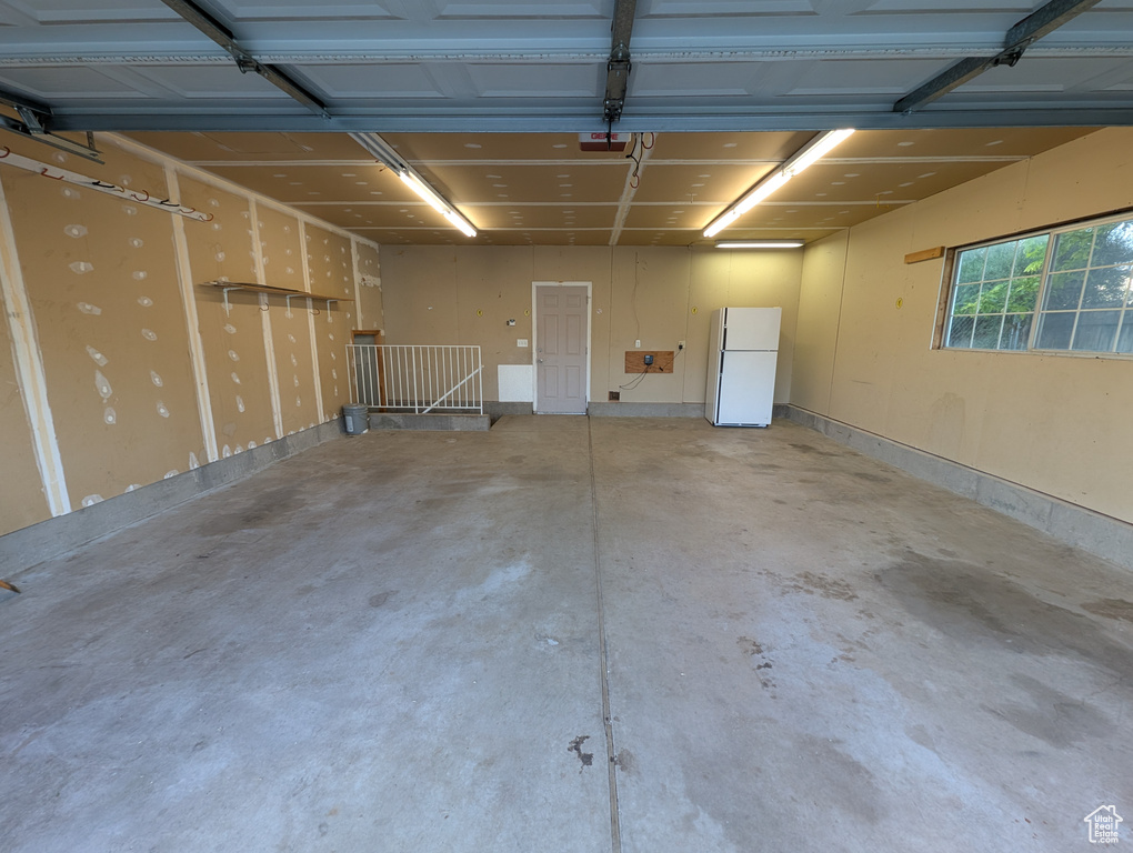 Garage featuring freestanding refrigerator and a garage door opener