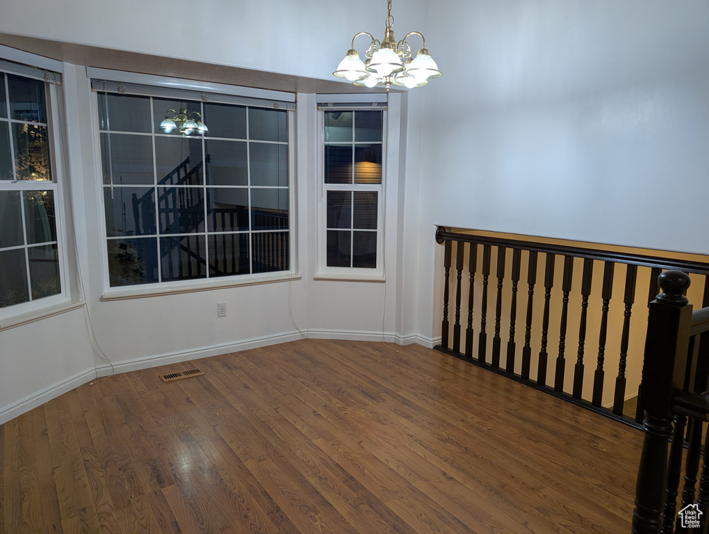 Spare room featuring a chandelier and wood finished floors