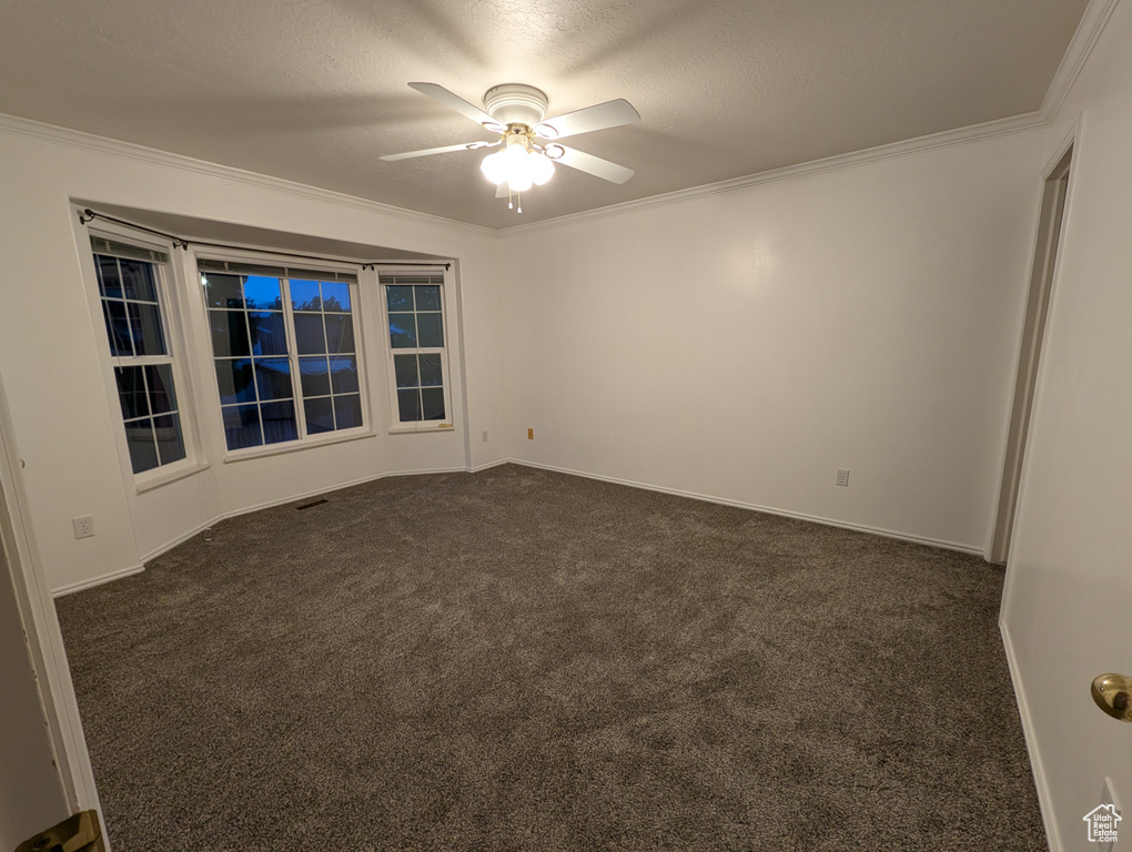 Unfurnished room with dark carpet, a ceiling fan, and ornamental molding