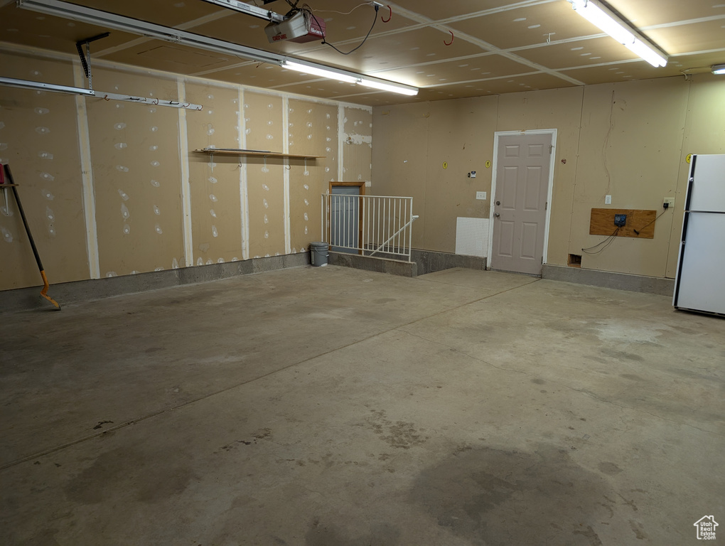 Garage with freestanding refrigerator and a garage door opener