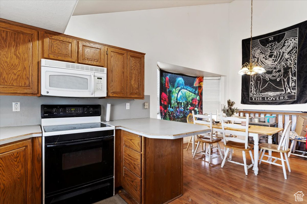 Kitchen featuring white microwave, range with electric cooktop, a peninsula, brown cabinets, and light countertops