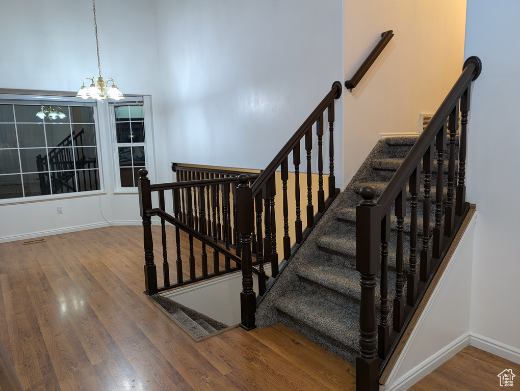 Staircase with a chandelier and wood finished floors