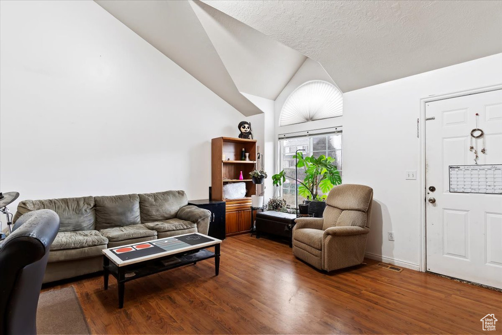 Living area with wood finished floors and vaulted ceiling