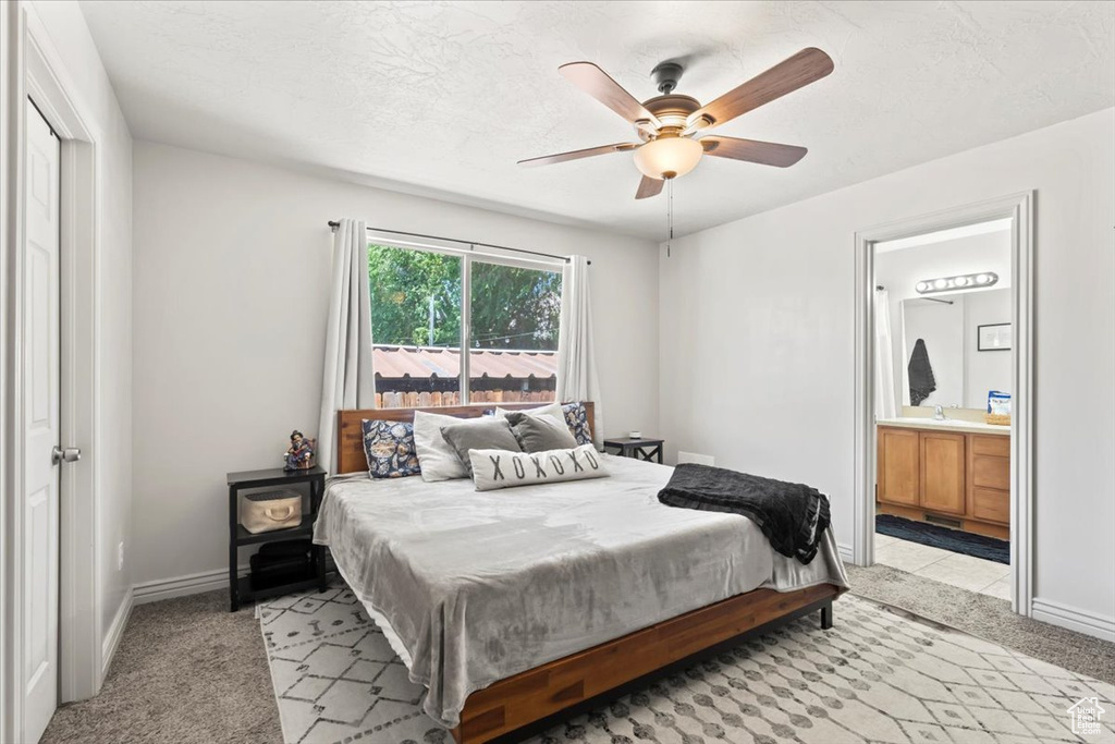Bedroom with light colored carpet, ensuite bathroom, and a ceiling fan