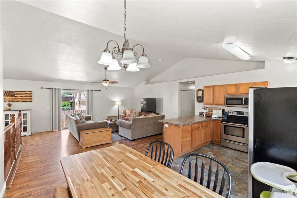 Dining room featuring vaulted ceiling, a chandelier, wood finished floors, and a ceiling fan