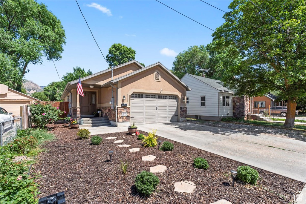 Ranch-style house featuring an attached garage, stucco siding, concrete driveway, and stone siding