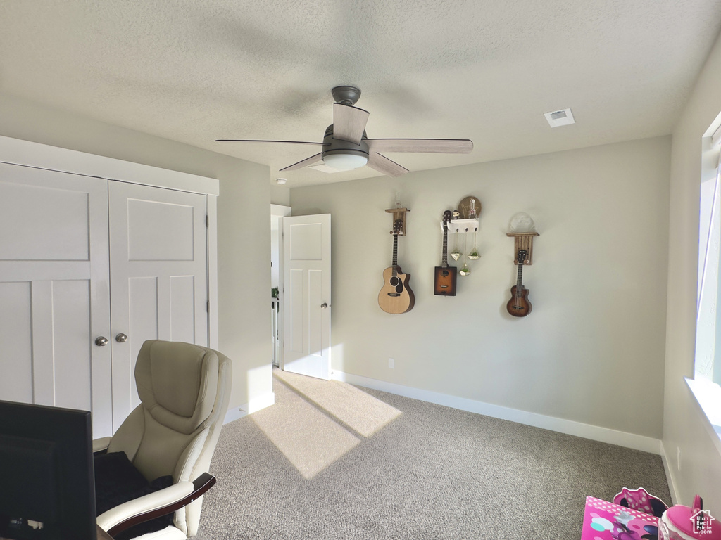 Home office featuring ceiling fan, carpet, and a textured ceiling