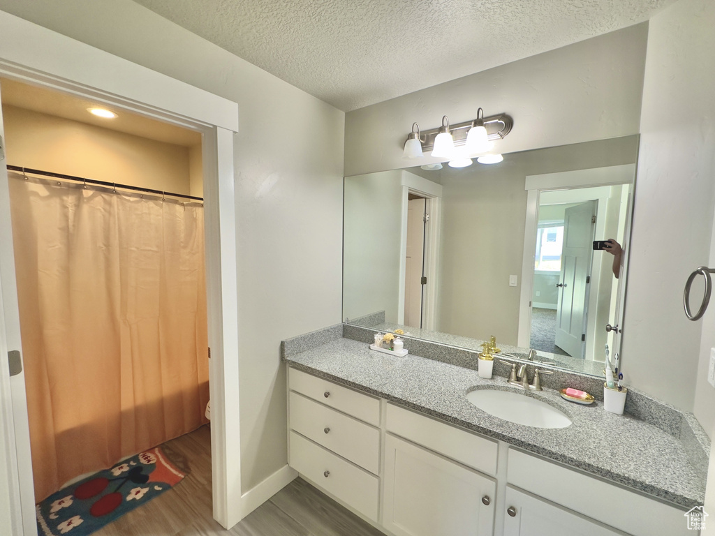Full bathroom featuring wood finished floors, vanity, a textured ceiling, and a shower with shower curtain