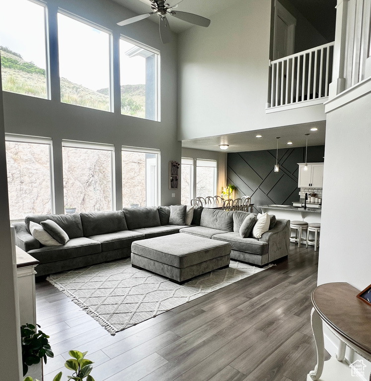 Living room featuring ceiling fan, healthy amount of natural light, a high ceiling, and wood finished floors