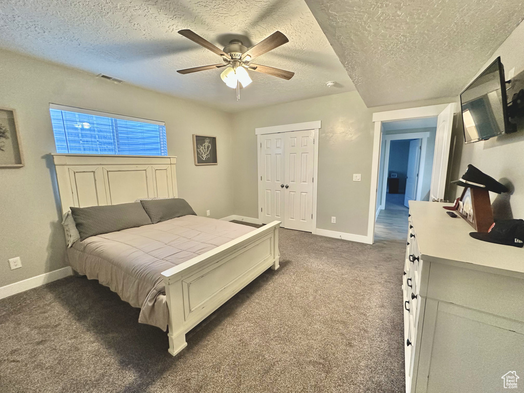 Bedroom featuring dark colored carpet, a textured ceiling, ceiling fan, and a closet