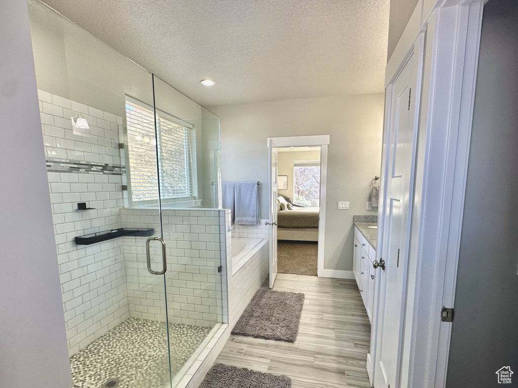 Full bath featuring a stall shower, a textured ceiling, ensuite bath, vanity, and wood finished floors