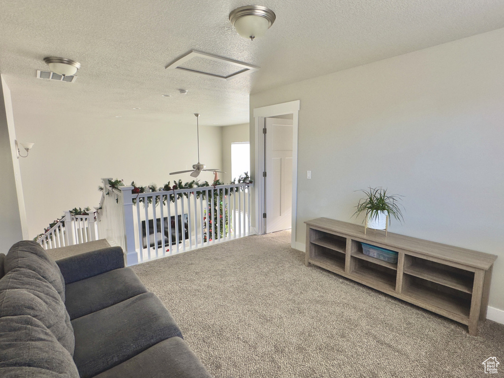 Living room with carpet, a textured ceiling, and a ceiling fan