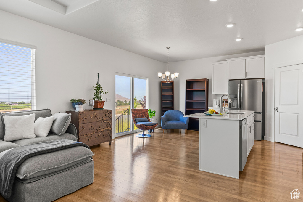 Kitchen with open floor plan, a chandelier, light countertops, white cabinets, and light wood-style floors