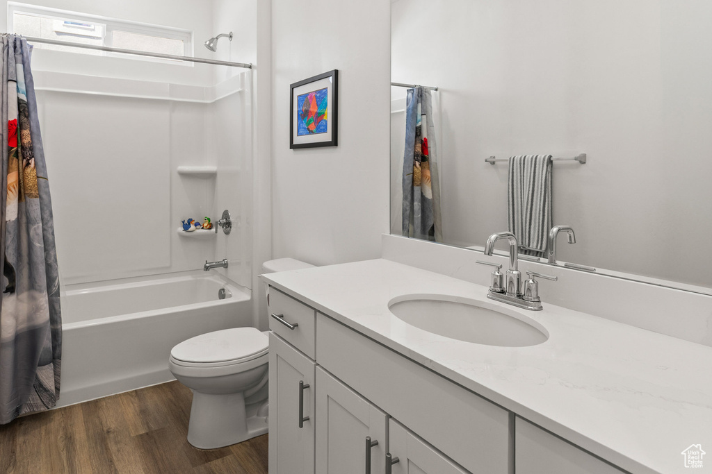 Full bathroom with vanity, shower / bathtub combination with curtain, and wood finished floors