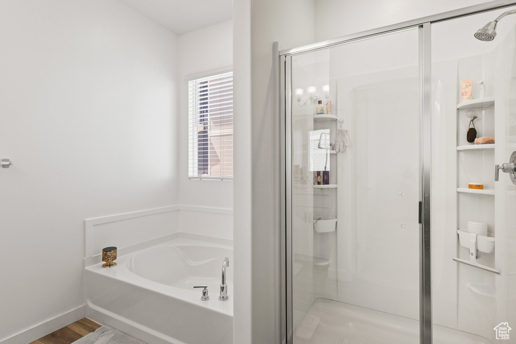 Bathroom featuring a shower stall, a garden tub, and wood finished floors