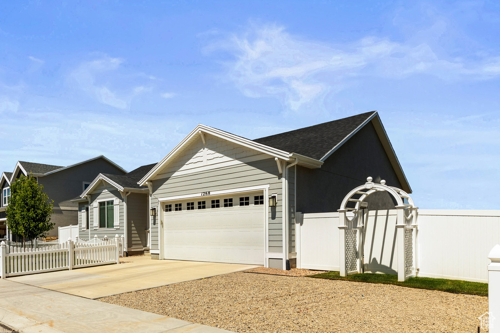 Ranch-style house featuring driveway, an attached garage, and a shingled roof