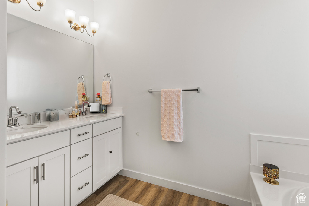 Full bath with double vanity, wood finished floors, and a bath