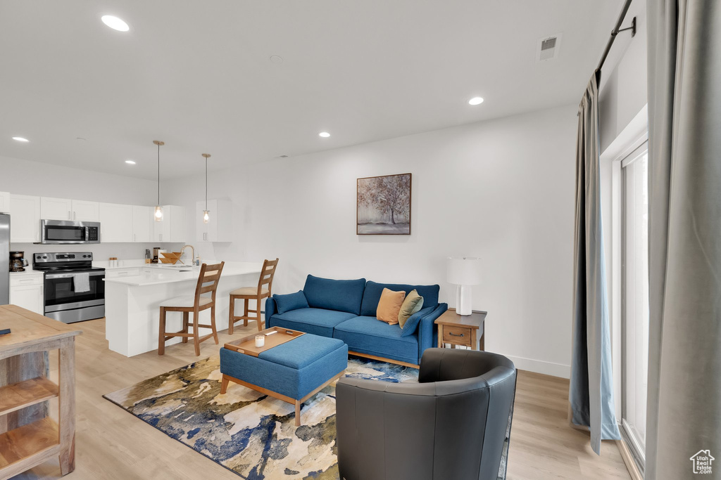 Living room with light wood-type flooring and recessed lighting