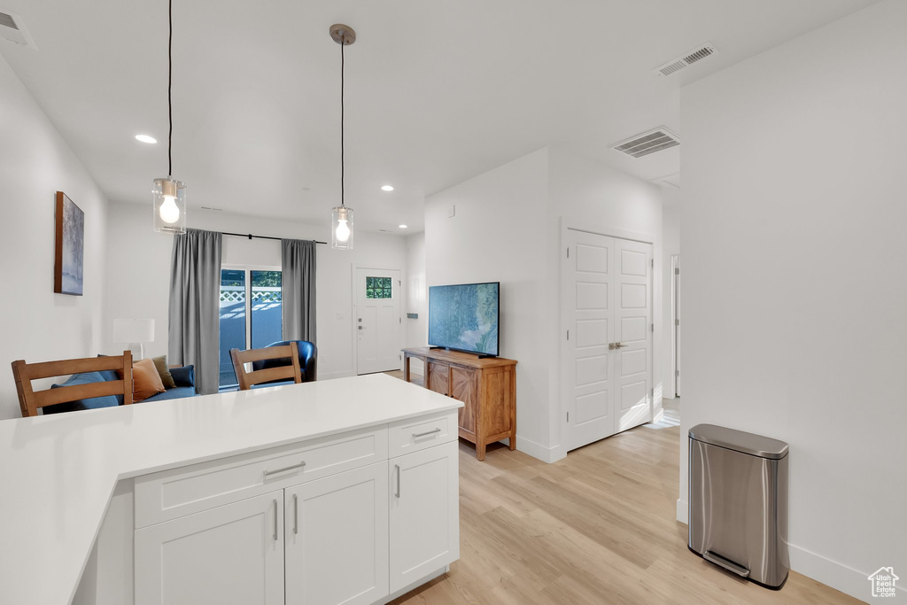 Kitchen featuring recessed lighting, white cabinetry, light wood-type flooring, hanging light fixtures, and light countertops