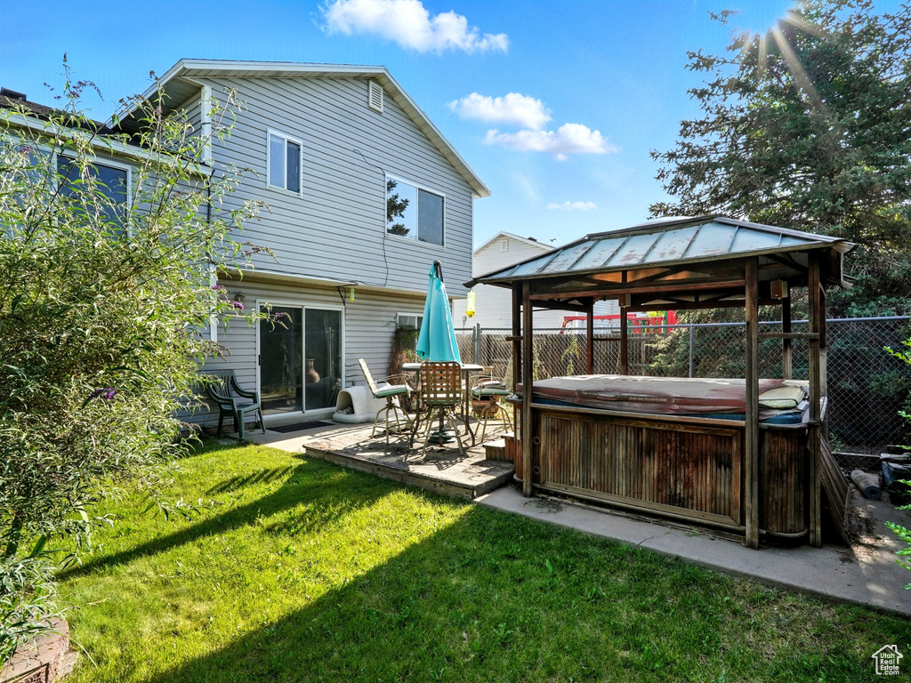 Rear view of house with a hot tub, a gazebo, and a patio