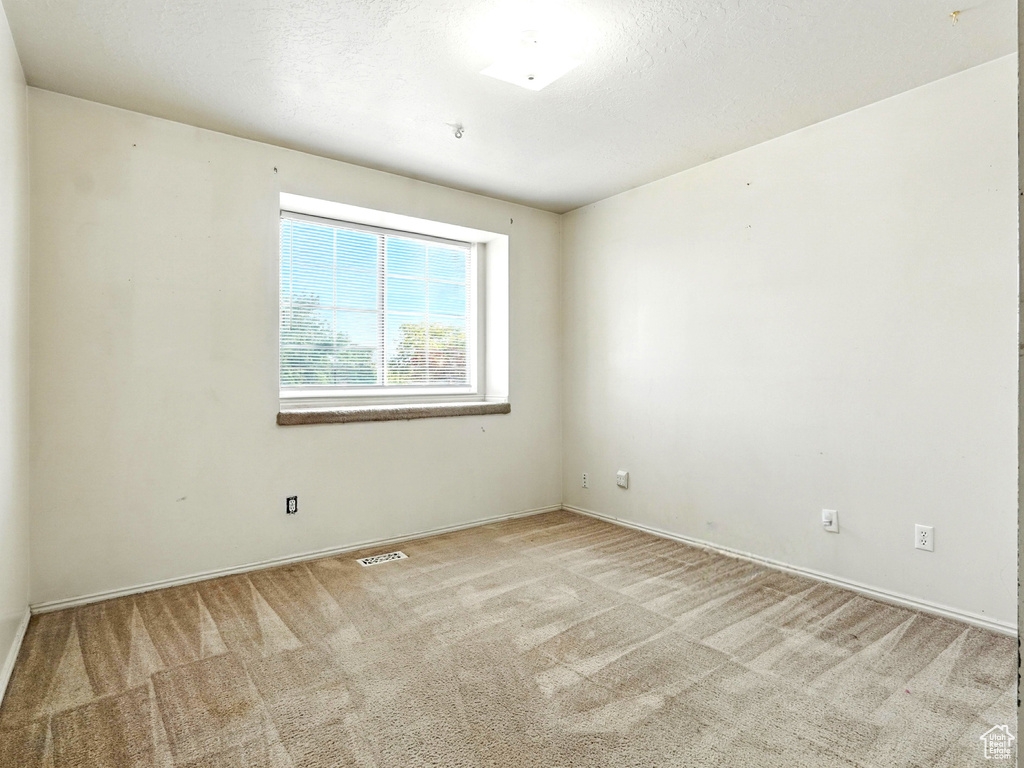 Unfurnished room featuring light carpet and baseboards