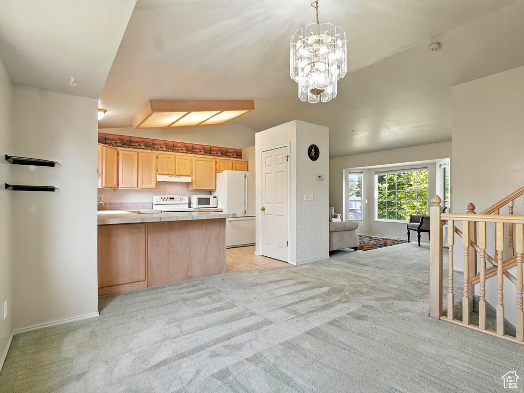 Kitchen featuring white appliances, light brown cabinets, light carpet, under cabinet range hood, and vaulted ceiling