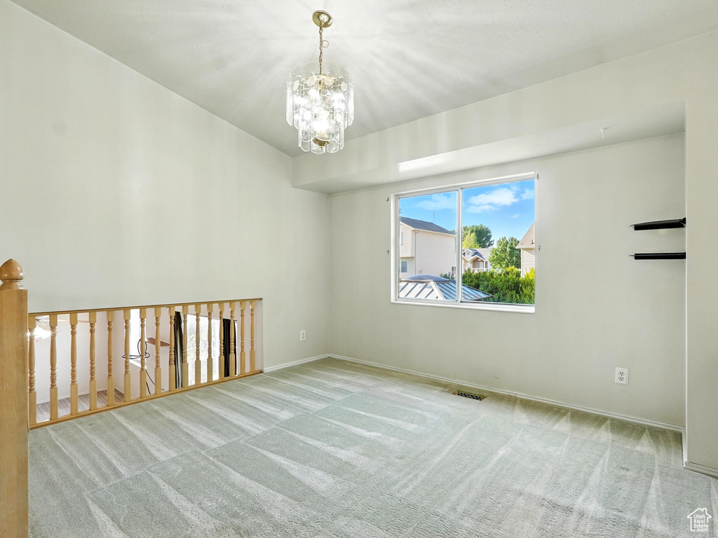 Spare room featuring carpet and a chandelier