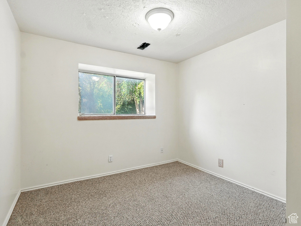 Carpeted empty room with baseboards and a textured ceiling