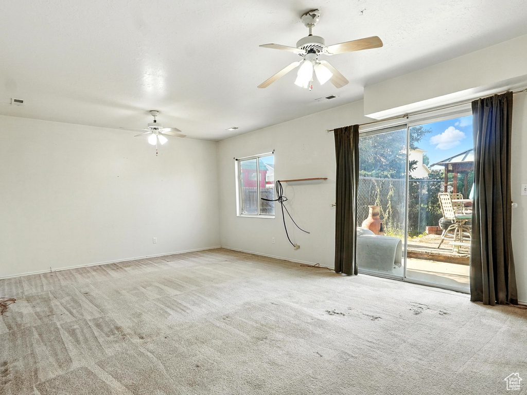 Empty room featuring a ceiling fan and carpet floors