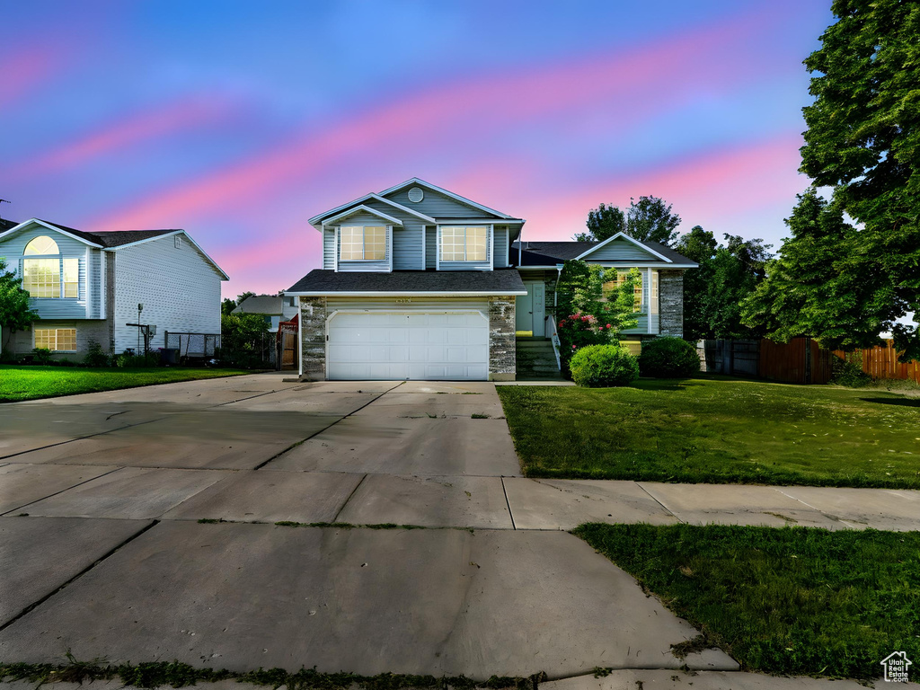 Traditional-style house featuring driveway, stone siding, and a garage