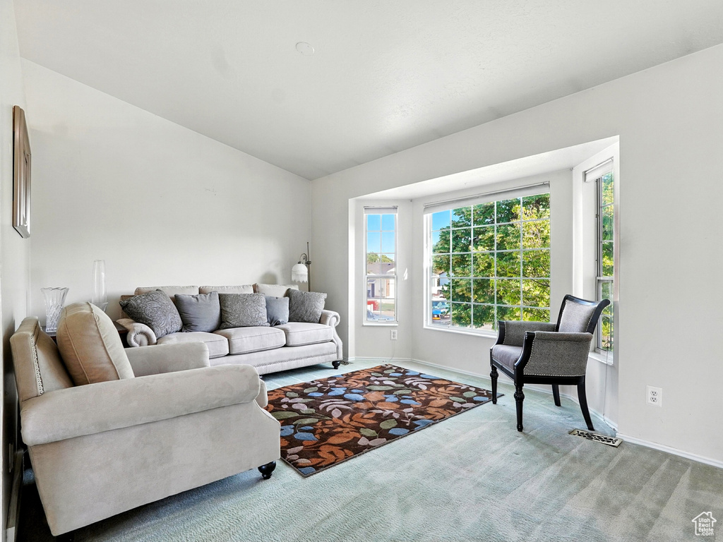 Living area featuring carpet flooring and vaulted ceiling