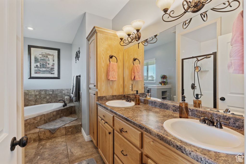 Bathroom featuring a chandelier, a bath, a shower stall, and double vanity